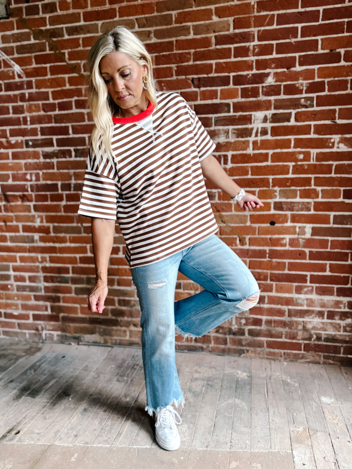 A woman wearing a brown and white striped short sleeve tee with a contrast ribbed neckline.