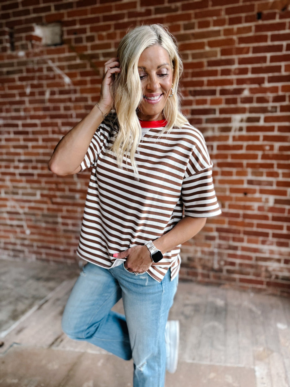 A woman wearing a brown and white striped short sleeve tee with a contrast ribbed neckline.