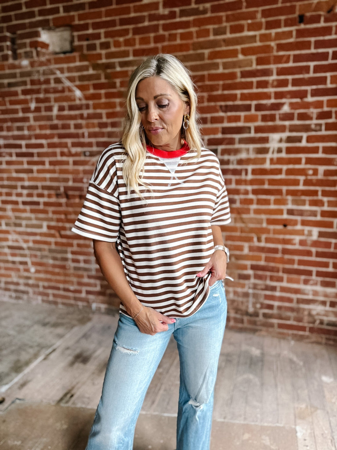 A woman wearing a brown and white striped short sleeve tee with a contrast ribbed neckline.